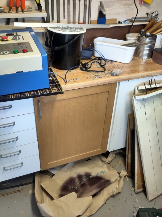 Verktygsbänk med utspridda skruvar och spillda föremål i en verkstad.