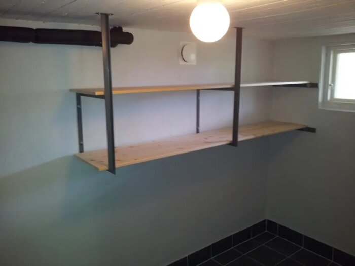 Svetsade konsoler med trähyllor monterade på väggen och taket i en källare.