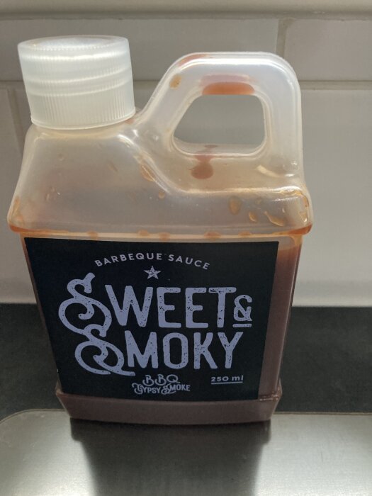 Flaska med BBQ-sås "Sweet & Smoky" från Gypsy Smoke, 250 ml stor, stående på en köksbänk.