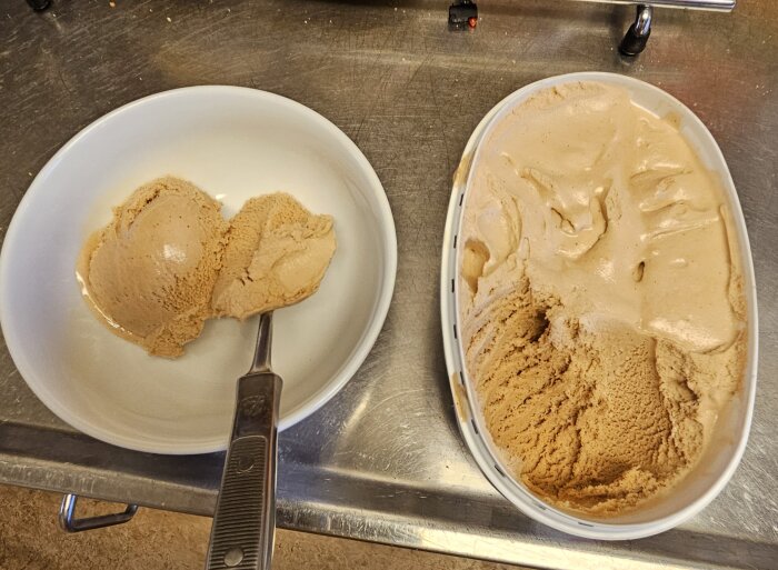 En vit skål med två kulor apelsin/chokladglass och en glasskopa. En halvfull halv oval glasslåda med samma glass bredvid.