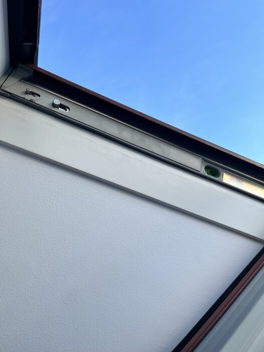 Takfönster på glänt mot blå himmel, visar låsmekanism och karm.