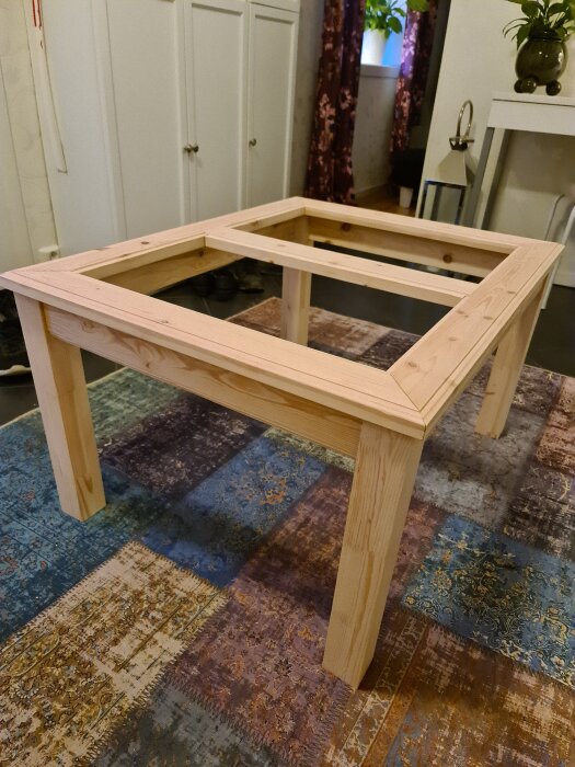 Träram till soffbord under konstruktion, på patchworkmatta inomhus.
