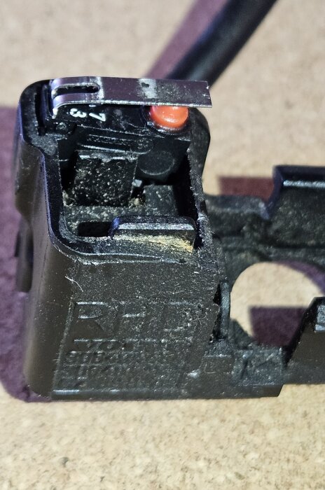 Elektrisk komponent i kassett med svåravlästa markeringar, inga platser för kabelskor, lödanslutningar pekar nedåt.