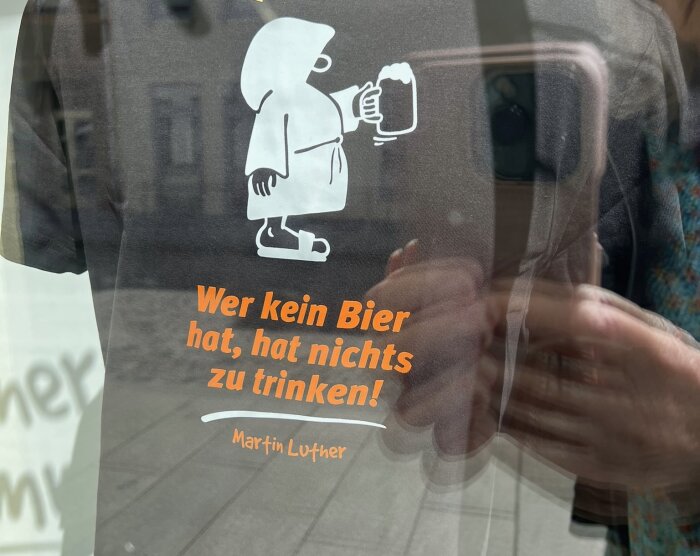 T-shirt med en tecknad figur som håller en ölmugg och texten "Wer kein Bier hat, hat nichts zu trinken! Martin Luther.