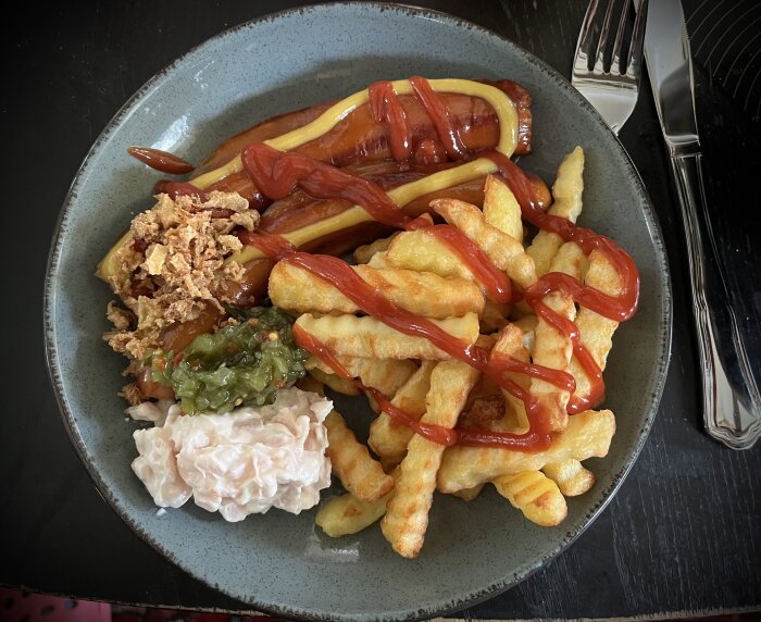 Tallrik med korv, pommes frites, räksallad, bostongurka, rostad lök, senap och ketchup.