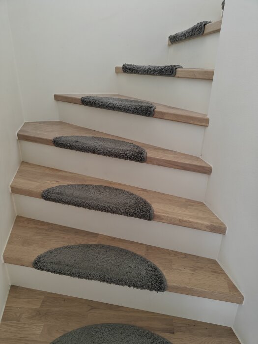 Trätrappor med grå mattskivor i en trappuppgång.