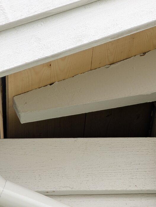 Råspont under takfot på ett uterum, omålad och delvis skyddad av tak. Takets hängränna syns.