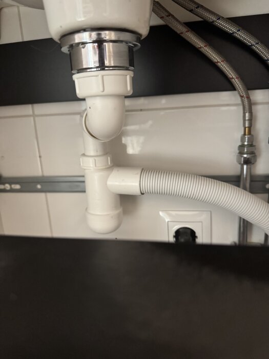 Under vasken med ett mjukt plaströr anslutet till vattenlåset, saknar packning och droppar.