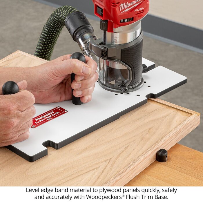 Person använder en fräs med en jig för kantlistning av träpaneler. Verktyget har två handtag för stabil styrning och kontroll.