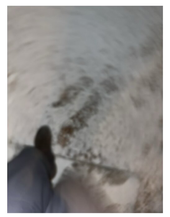 Osäker bild med suddig bakgrund, snötäckt mark, och en stövel synlig. Leverans från Budbee.
