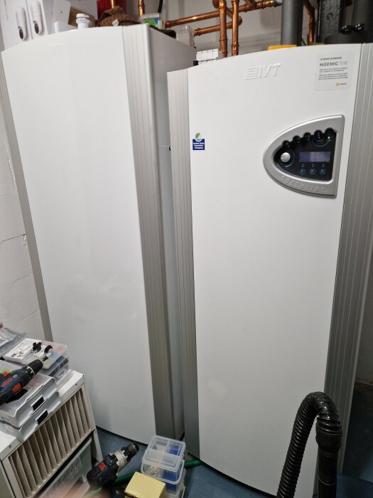 IVT Greenline varmvattenberedare och pump i ett teknikutrymme, omgivna av verktyg och tillbehör.