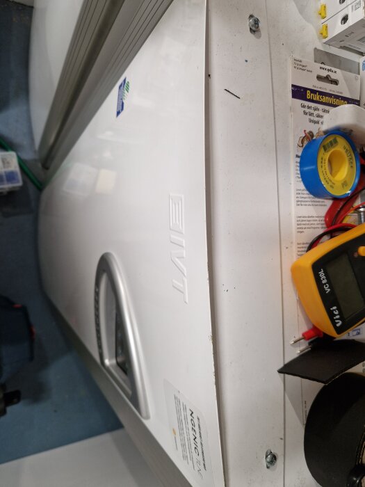 Varmvattenberedare från IVT Greenline med frontpanel utan synliga skruvar, omgiven av verktyg och bruksanvisning på ett vitt bord.