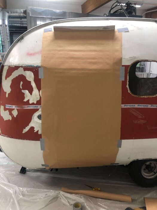 Papperstejpning på husvagnens sida för att skapa en dörrmall vid renovering.