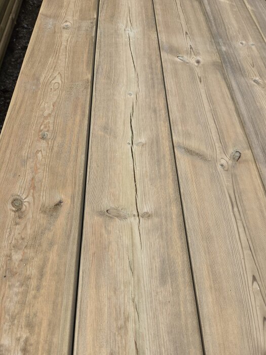 Brädor med sprickor och kvistar, marknadsförda som premiumvirke för altanbygge, ifrågasätts angående kvalitet och reklamation.