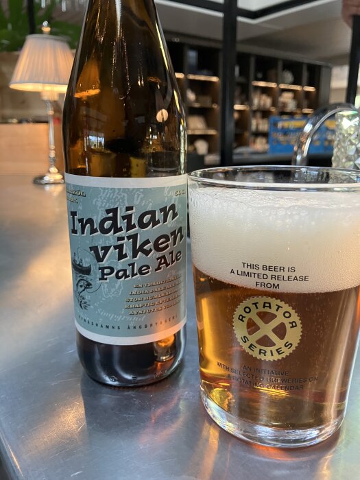Flaska och glas med Indian Viken Pale Ale från Nynäshamns Ångbryggeri på ett bord.