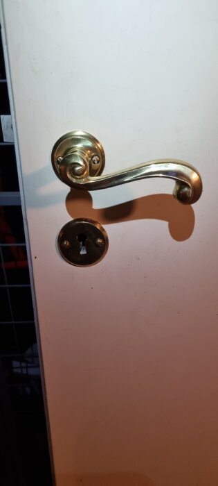 Gammaldags metallhandtag och nyckelhål på en funkisinnerdörr från 1939.