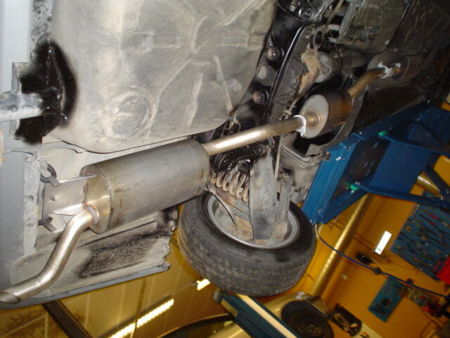 Rostfritt avgassystem monterat under en äldre Mercedes, visas från bilen lyft i en verkstad.