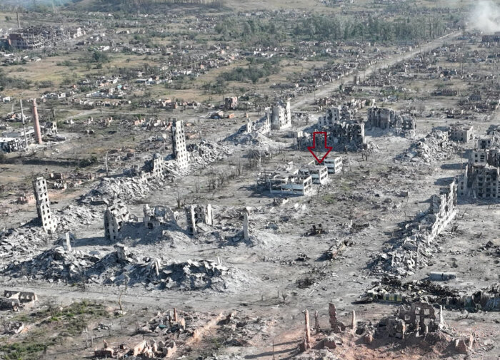 Ruiner och förstörelse i Vovtjansk med utbrända byggnader och sönderfallna strukturer, april 2015. En röd pil pekar på en viss byggnad.