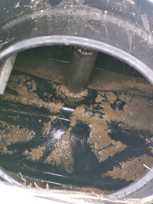Insidan av en skadad reningstank med en bula och jordavlagringar. En röranslutning syns ovanför bulan. Tanken är av märket Upnor clean 1.