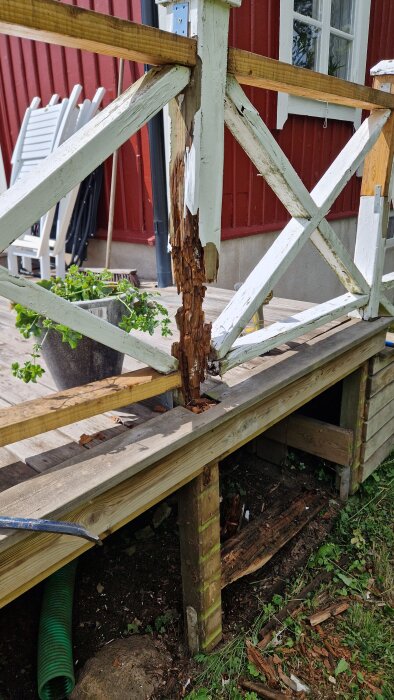 Ruttna träreglar på altan med vitmålade krysstolpar, visar skadorna från bristande grundisoleringspapp och olämplig konstruktion.