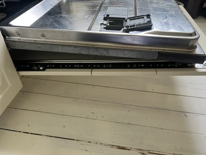 Integrerad diskmaskin i ett kök med synlig monteringskonstruktion för kökslucka, sett uppifrån med avlägsnad lucka på golvet.