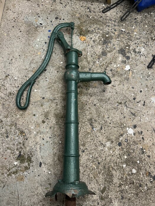 Grön trädgårdspump med skadad fot liggande på marken, märkt med nummer 15.