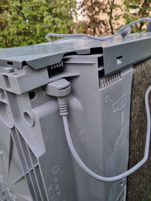 Nätsladd fastsatt i grå diskmaskinspanel utomhus, svår att lossa enligt inläggsfråga.
