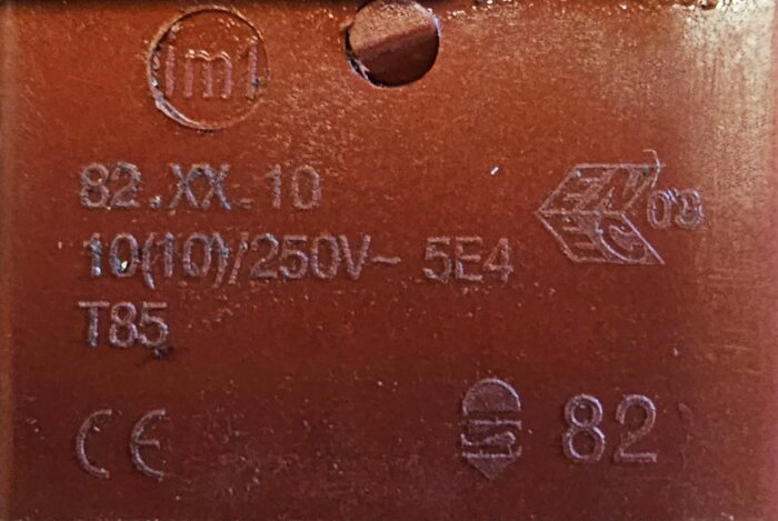 Brun microswitch med artikelnummer och symboler inklusive "82.XX.10" och "250V" för en Karcher biltvätt, fotograferad på nära håll.