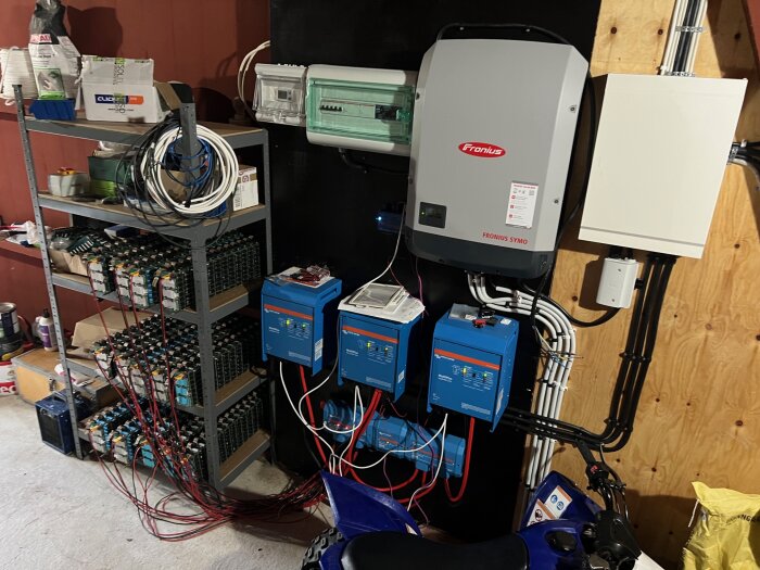 Solcellsanläggning med Fronius Symo inverter, Victron Multiplus enheter och hemmabyggt batteripack synligt i ett teknikrum.