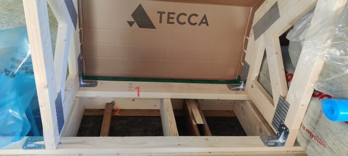 Träställning med märkning för luftspalt och ångspärr vid byggprojekt. Siffror 1 och 2 markerar potentiella fästpunkter. Märke "TECCA" syns.