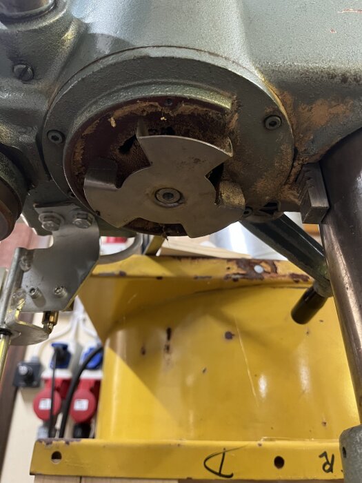 Fläktkåpa med avlägsnad fläkt under motor, visar skruvar och del av växelhusets axel.