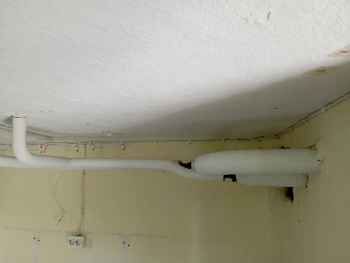 Vita stålrör i takvinkel, del av köksombyggnad. Rören löper horisontellt längs källartaket och bör flyttas.