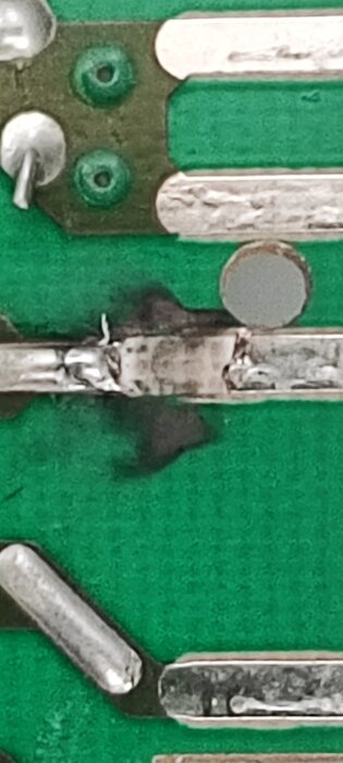 Närbild av ett kretskort med en bränd ledningsbana och lödfogar, använd för reparation av torktumlarens programkort.
