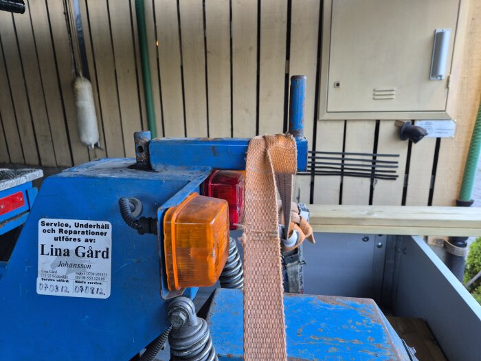 Eldriven flakmoppe av märket Transportel 950 med metallstång bakom sadeln och orange varningslampa, omgiven av träpanel och verktyg.