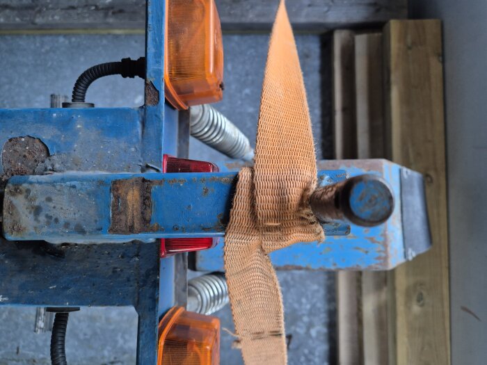 Närbild av draganordning på en eldriven flakmoppe, med orange spännband och reflekterande lampor.