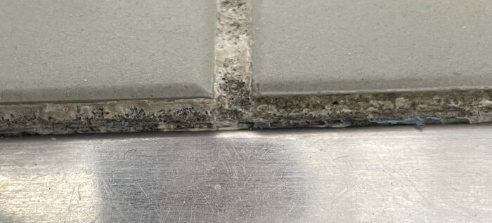 Närbild på fog mellan klinkerplattor med synlig plastkant undertill.