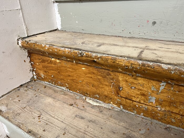 Gammal trätrappa med bortskrapad färg och synligt trä. Plansteg och sättsteg med sliten, grov yta, rester av tidigare behandling synliga.