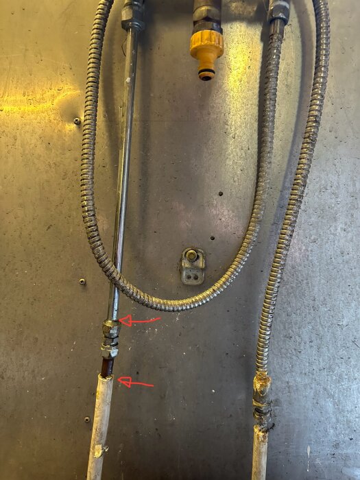 Vattenrör i garaget med två röda pilar som markerar platser där små läckor uppstår.