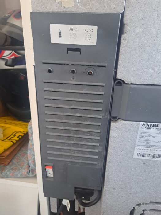 Grå lucka på Nibe F750 med temperaturkontrollsymboler, visar osäkerhet kring hur man öppnar luckan.