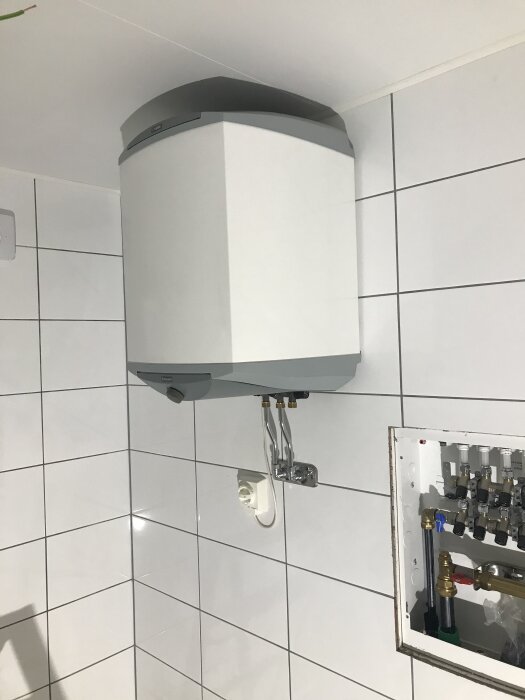 Varmvattenberedare, Nibe Eminent 55L, installerad på väggen i ett kaklat badrum.