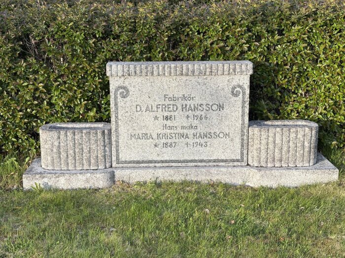 Gravsten för D. Alfred Hansson och Maria Kristina Hansson på en gräsmatta med buskar i bakgrunden.
