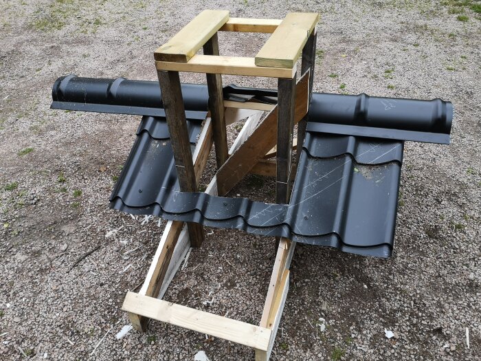 Beslaget till skorsten och luftrör visas med svart plåt monterad på träkonstruktion, förberedd för takläggning.