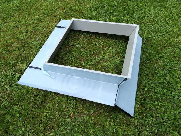 Nytt plåtbeslag till skorsten och luftrör ligger på gräs.