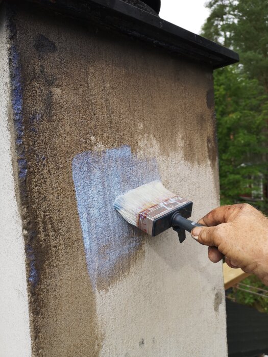Person målar skorstenens yta med en pensel.