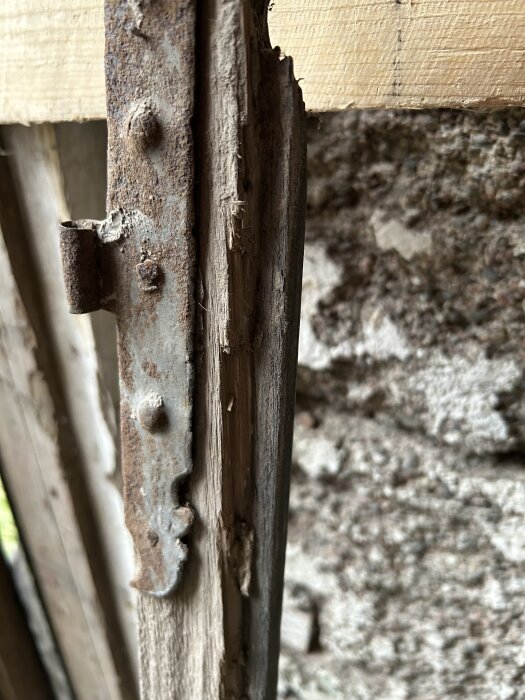 Skadad fönsterbåge med rostig metall och delvis sönderfallande trä.