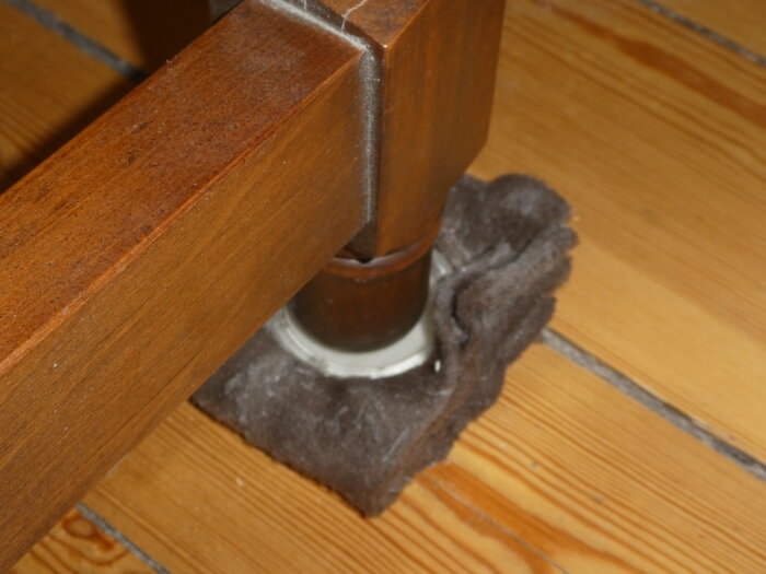 Stolsben med fleece som skydd på ett 120-årigt furugolv, vilket har orsakat mörka fläckar på golvet.