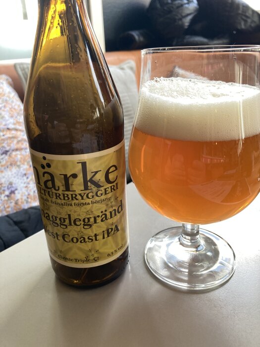 Flaska och glas med Härke Kulturbryggeri's Nagglegränd West Coast IPA, fyllt glas med skum på toppen.