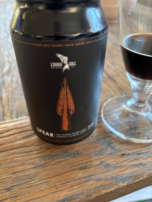 Burk med Lough Gill Brewing Co's "Spear" Imperial Oatmeal Stout på 13%, bredvid ett glas delvis fyllt med mörk öl.
