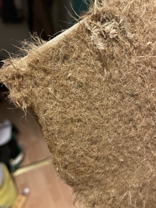 Närbild av ett fiberrikt material som kan vara jute, potentiellt mixat med asbest, visas för inspektion.