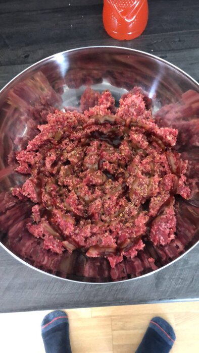 Hemmagjord hamburgarfärs kryddad och blandad i en stor silverskål på en köksbänk, redo för att formas till hamburgare.